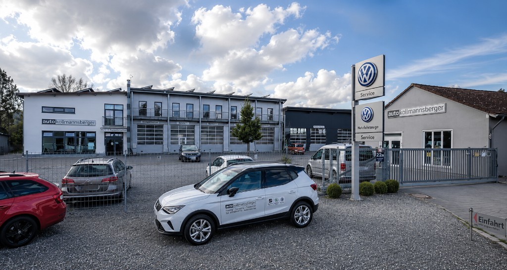 Außenansicht des Autohauses Auto Kollmannsberger in Palzing: Werkstattgebäude, Volkswagen-Service-Pylon und Firmenfahrzeug.